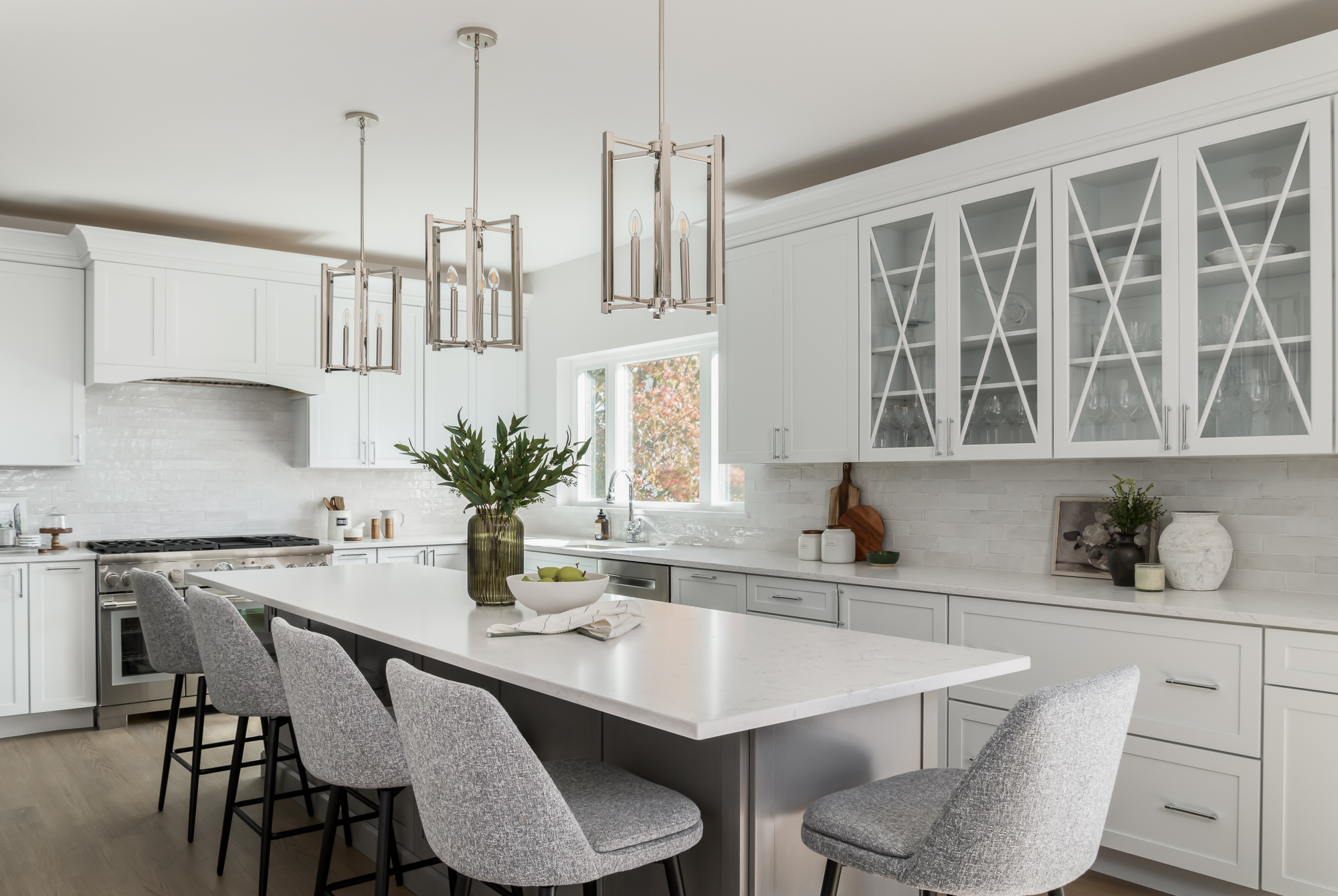 A bright, award-winning transitional kitchen with a marble island and glass-front cabinetry by Yellow Stone Interior Design